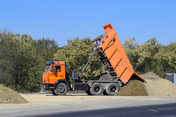 The dump truck unloads rubble. The truck dumped the cargo. Sand and gravel. Construction of roads