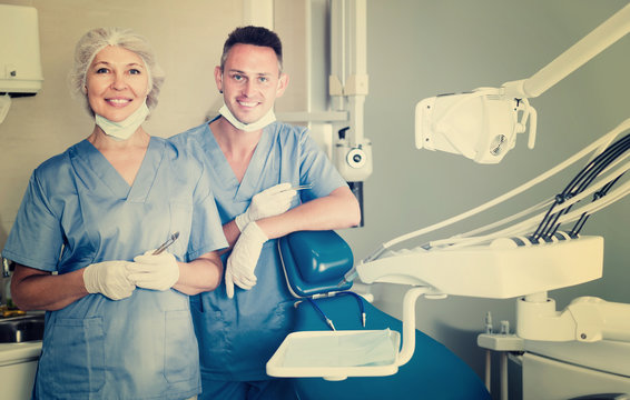 Portrait of professional cheerful dentists standing in medical office