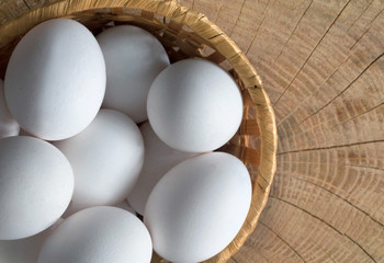 Chicken egg in a basket on a wooden background, close-up.