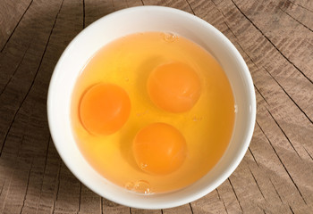 Yolk in a ceramic dish on a wooden background, top view