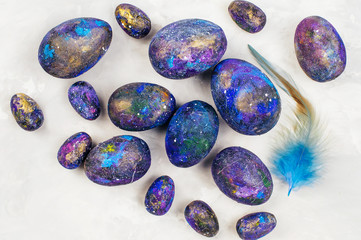 Galaxy Easter eggs with feather on grey concrete background
