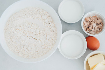 Preparation of the dough. The rolled out dough with the ingredients - flour, eggs,  and cooking instruments . On a white wooden background. Top view