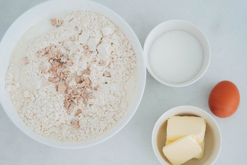 Preparation of the dough. The rolled out dough with the ingredients - flour, eggs,  and cooking instruments . On a white wooden background. Top view