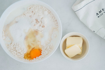 Preparation of the dough. The rolled out dough with the ingredients - flour, eggs,  and cooking instruments . On a white wooden background. Top view