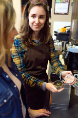 Beautiful young woman customer choosing tea sold by weight in organic shop.