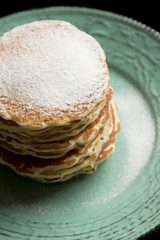 American pancakes with sugar from above on a pastel green rustic plate