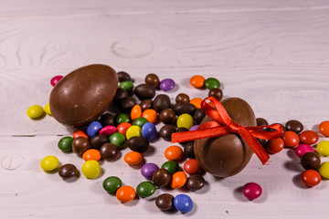 Chocolate easter eggs and multicolored candies on wooden table