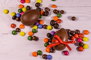 Chocolate easter eggs and multicolored candies on wooden table. Top view
