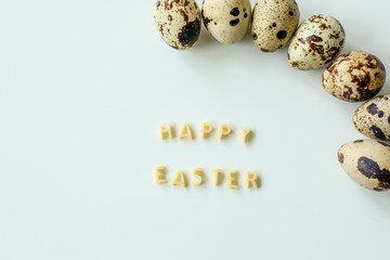  Happy easter, inscription from the letters of pasta, next to quail eggs on white background