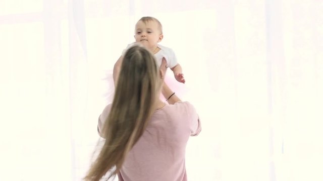 Happy mother spinning with her little baby. Slow motion