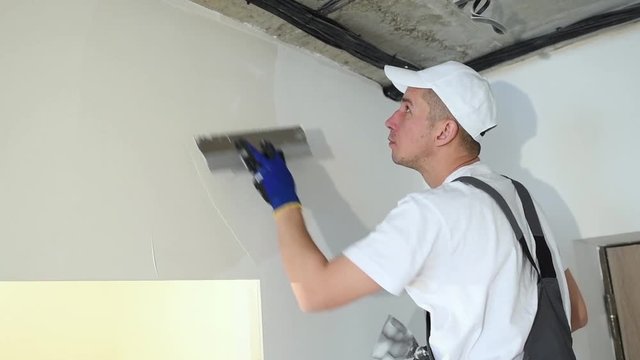 refurbishment. Worker spackling a wall with putty