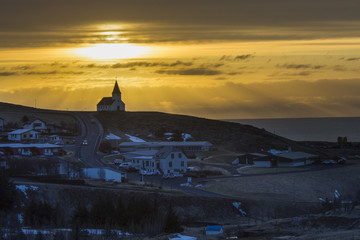 Fototapeta na wymiar Vik city and countryside church on hill in winter with traveller in early morning with a beam of sunlight.