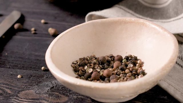 Bowl of pepper balls on dark wooden table.
