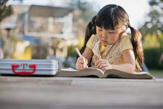 Girl coloring in coloring book outdoors