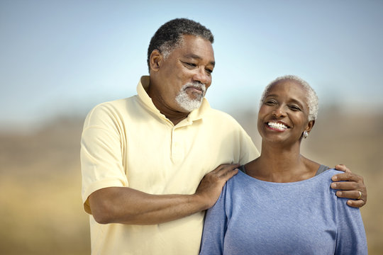 Smiling senior couple happily standing on a beach.