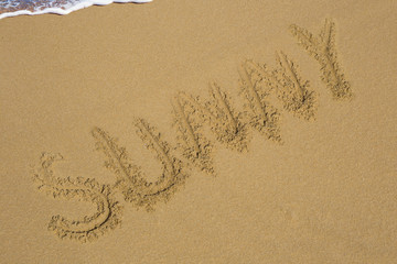 Handwriting words SUNNY DAY on sand of beach