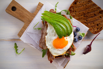 Avocado, egg and bacon sandwich. Fried egg and avocado on toast. Panini. Healthy tasty food for breakfast or brunch