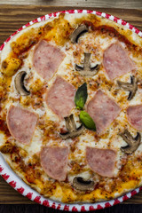 Italian pizza on a thin dough with ham and mushrooms