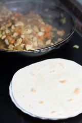 Cooking burrito in a pan with chicken, pepper, tomato for fajitas typical Latin America food