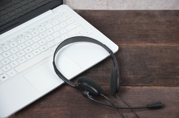 Laptop and earphones on a wooden table. Journalist, online training, remote work, online games