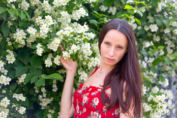 A pretty girl near the bush of fragrant jasmine