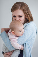 a young mother holds a baby in her arms and kisses her daughter in the head. Mom is going through