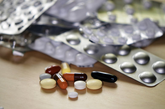 Some tablets and capsules in front of a lot of blurred packaging