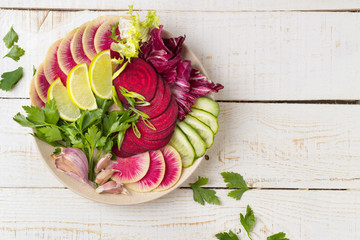 Fresh salad with beets, watermelon radish, cucumber, parsley, lime, garlic, olive oil, mix salads. Healthy concept. White background. Flat lay. Top view.	
