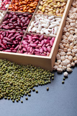 Different types of legumes beans. In wooden box.Varieties of beans.Top view.Closeup.Texture.Copy space.On dark stone background