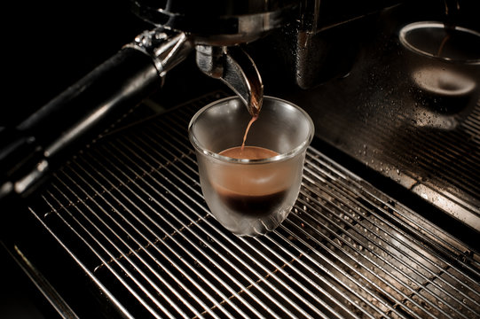 Top view of professional coffee machine pouring a fresh and aromatic coffee into a cup