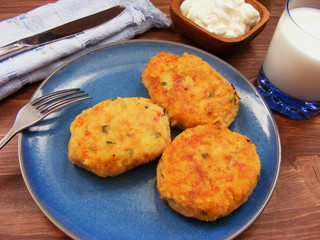 Rissoles of ham, cheese  and potatoes on blue plate, milk in glass and sour cream in wooden bowl with cover