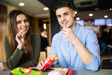 Couple in a restaurant or diner eating a hamburger and potato fries and have fun