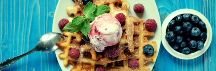 Plate of belgian waffles with ice cream and fresh berries - raspberries and blueberries.top view close-up.