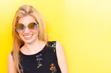 happy young woman smiling at yellow wall