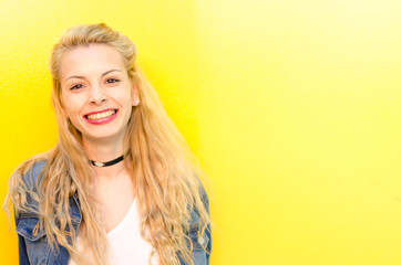 happy young woman smiling at yellow wall