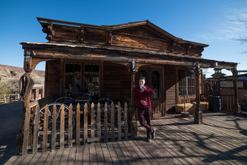 Man drinking water in front of old wooden house in cowboys county village