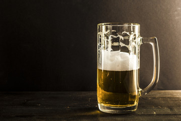 Incomplete mug with beer on a dark background.