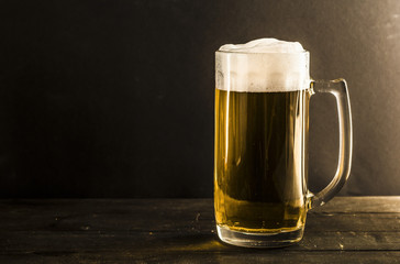 A mug of beer on a wooden pub desk.