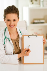 Happy medical doctor woman pointing in clipboard