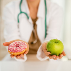Closeup on medical doctor woman giving a choice between apple an