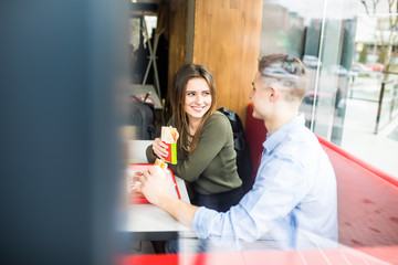 Happy smiling woman and a handsome man are enjoying their delicious and tasty burgers