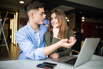 Happy couple at cafe looking at laptop. Couple with laptop in cafe