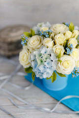 Exquisite spring bouquet. Blue and white wedding flowers. Wedding floral decorations. Floristic composition in a sky-blue vase. Roses, lilies and violets. Macro close up. Perfect girl gift idea
