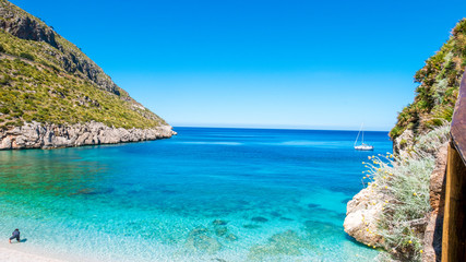 Fototapeta premium A sailing boat into the turquoise Mediterranean Sea, at San Vito Lo Capo, Sicily, Italy.
