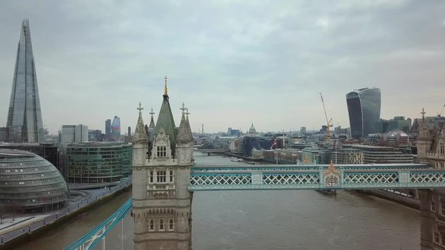 London, United Kingdom - 4K aerial view of famous Tower Bridge on a cloudy morning with skyscrapers and other famous landmarks behind