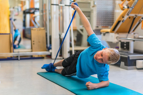 Kind bei der Physiotherapie trainiert mit einem Physiotape auf einer Gymnastikmatte