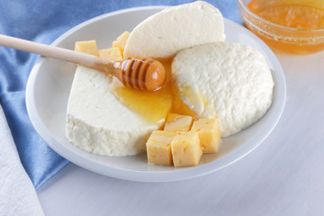 Cheese, milk assortment on white background, white cheese and honey on a blue napkin, wooden background, wooden stick for honey, top view, cheese on white plate, kefir in a glass, pop art