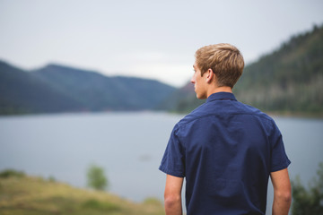 Teenage boy looking out over lake and mountain scenery