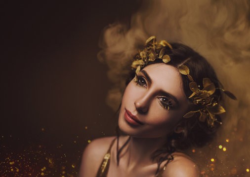 Close-up portrait. Girl with creative make-up and with golden eyelashes. The Greek goddess in a laurel wreath with flowers and handmade roses. Art Photo
