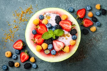 Zelfklevend Fotobehang Healthy summer breakfast concept, fruit salad in carved watermelon. Watermelon bowl with yogurt, chia seeds, fresh berries, bee pollen. © sveta_zarzamora